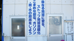 看板「母なる地球に愛を、ストップ地球温暖化　こまめな節電、ガソリン・紙・水の節減をしよう」